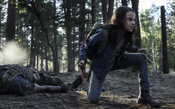 HD wallpaper featuring Dafne Keen as Laura Kinney/X-23 in Logan movie, crouched in a forest, with claws extended, ready for action.