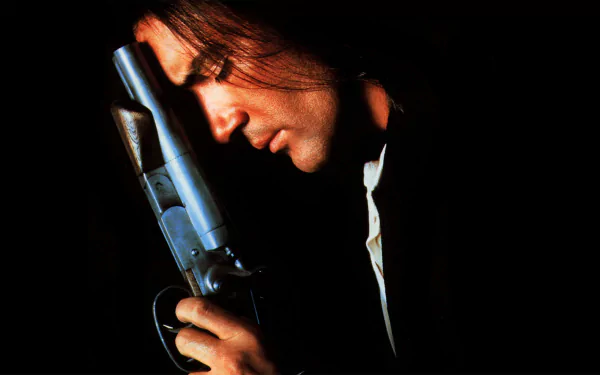 HD PC desktop wallpaper: moody Desperado movie scene showing a man in profile cradling a pistol, his face lit against a deep black background.