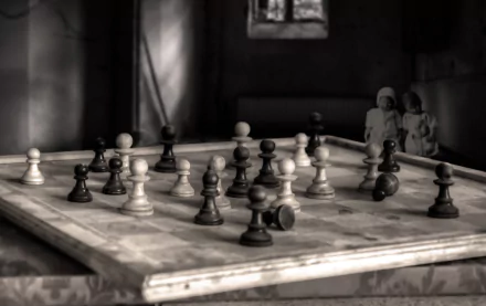 Sepia-toned black and white HD desktop wallpaper showcasing a vintage chessboard with detailed chess pieces in a dimly lit room, highlighting man-made strategy and design.