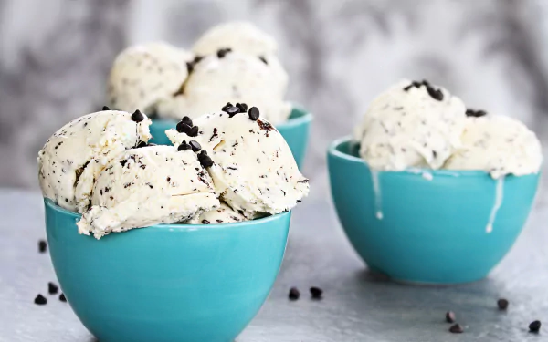 A close-up of creamy cookies and cream ice cream scoops in blue bowls, captured in 4K Ultra HD as a vibrant PC desktop wallpaper background.