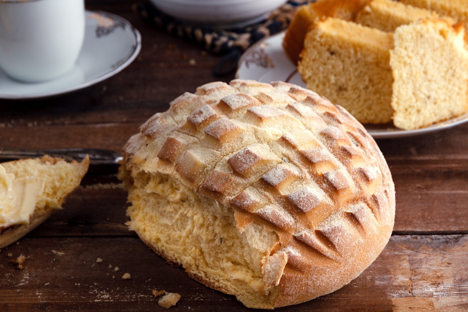 HD PC desktop wallpaper and background — food, bread: rustic round loaf with diamond-cut crust, a torn slice and plate of slices on a wooden table.