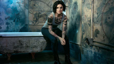 HD PC wallpaper: brunette with short hair and arm tattoos crouches in a grungy bathroom, moody TV-show style lighting and worn industrial backdrop.