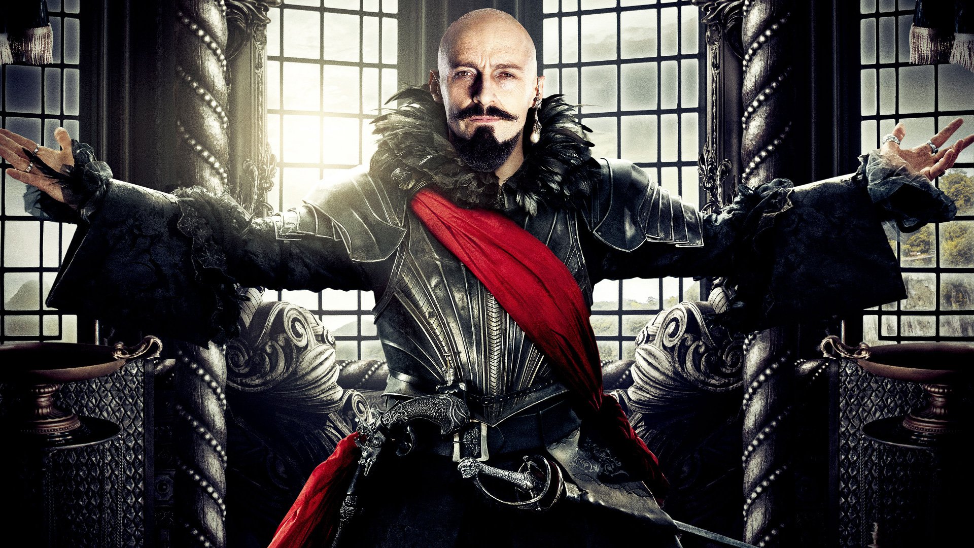 HD PC wallpaper of a bald, mustached villain in ornate black leather with a red sash, arms outstretched in a grand chamber — promotional image from the movie Pan