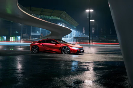 A sleek red BMW i8 supercar parked under modern architecture at night, captured in a 4K Ultra HD desktop wallpaper showcasing its dynamic design.