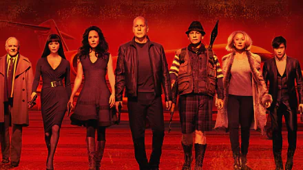 HD desktop wallpaper for the film RED 2: a red-toned lineup of armed characters striding toward the camera against a fiery backdrop.