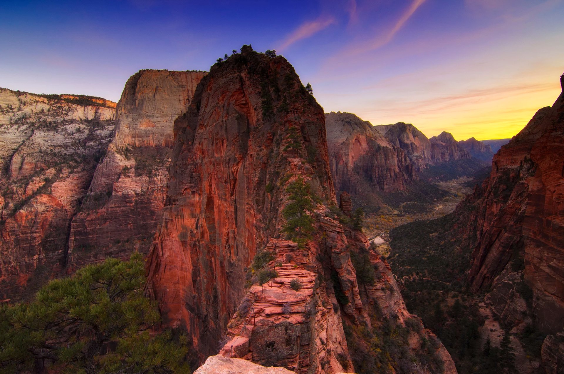 Zion National Park canyon at sunset in Utah, dramatic red cliffs and a rugged ridgeline overlooking a valley — HD desktop wallpaper background showcasing canyon nature.