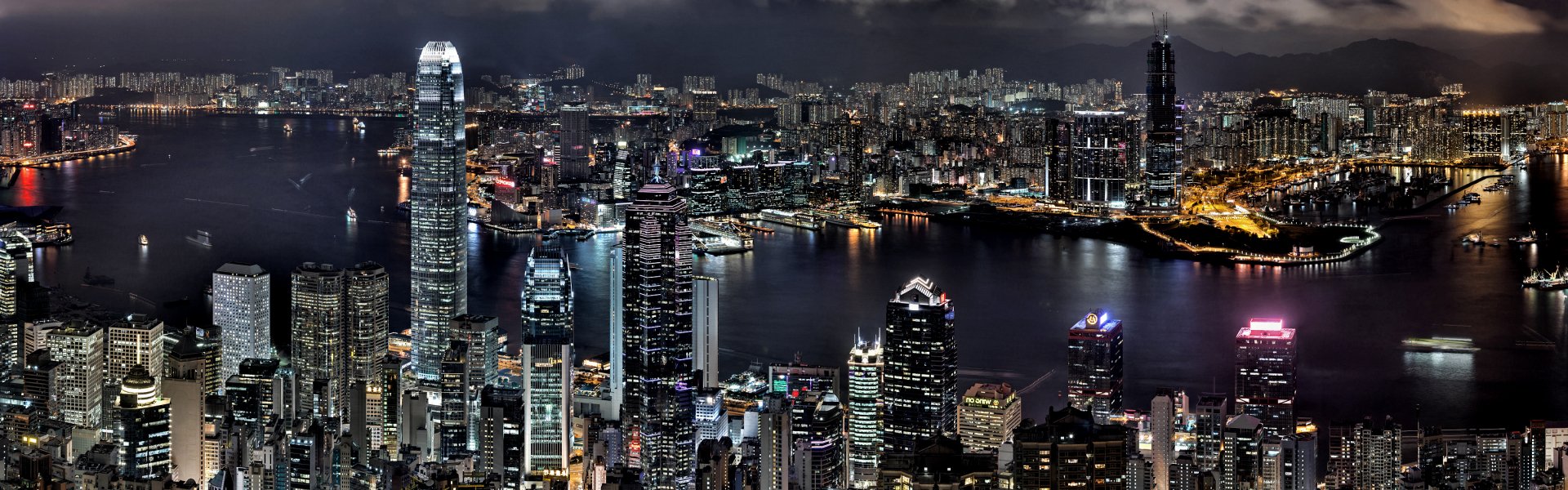 A stunning HD wallpaper showcasing the vibrant skyline of Hong Kong at night, featuring illuminated skyscrapers reflecting on the water.