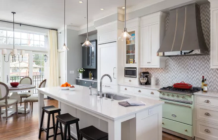 HD desktop wallpaper of a modern kitchen featuring a central island with bar stools, white cabinetry, stainless steel appliances, and large windows letting in natural light.