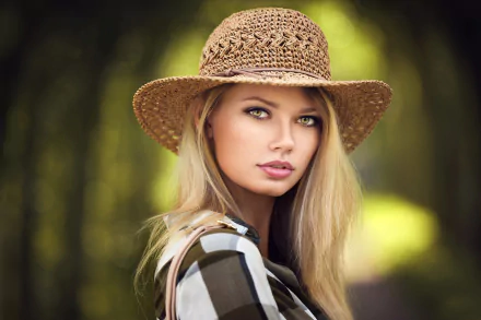 Blonde woman model with yellow eyes wearing a woven hat, captured in sharp focus against a soft, blurred natural background in this HD PC desktop wallpaper.