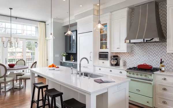 HD desktop wallpaper of a modern kitchen featuring a central island with bar stools, white cabinetry, stainless steel appliances, and large windows letting in natural light.