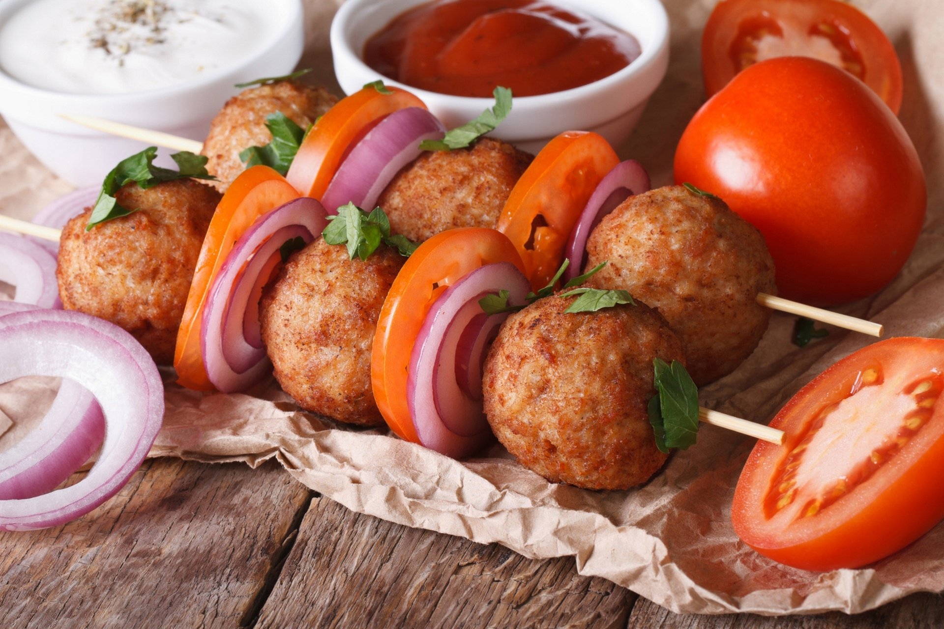 HD PC desktop wallpaper showing barbecue meatballs skewered with slices of tomato and red onion, garnished with fresh herbs alongside dipping sauces.