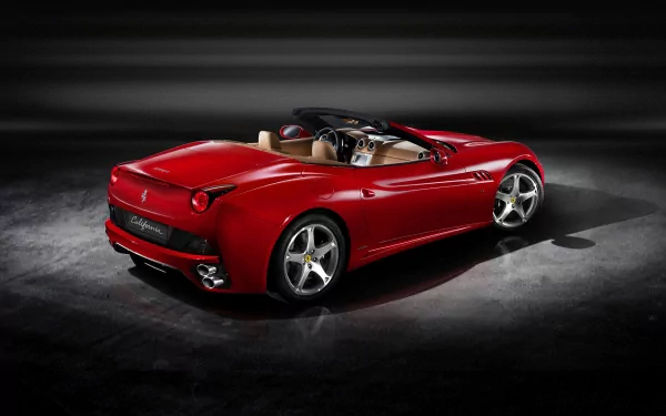 Red Ferrari California grand tourer convertible under studio lights, rear three-quarter view — HD PC desktop wallpaper background showcasing the luxury car.