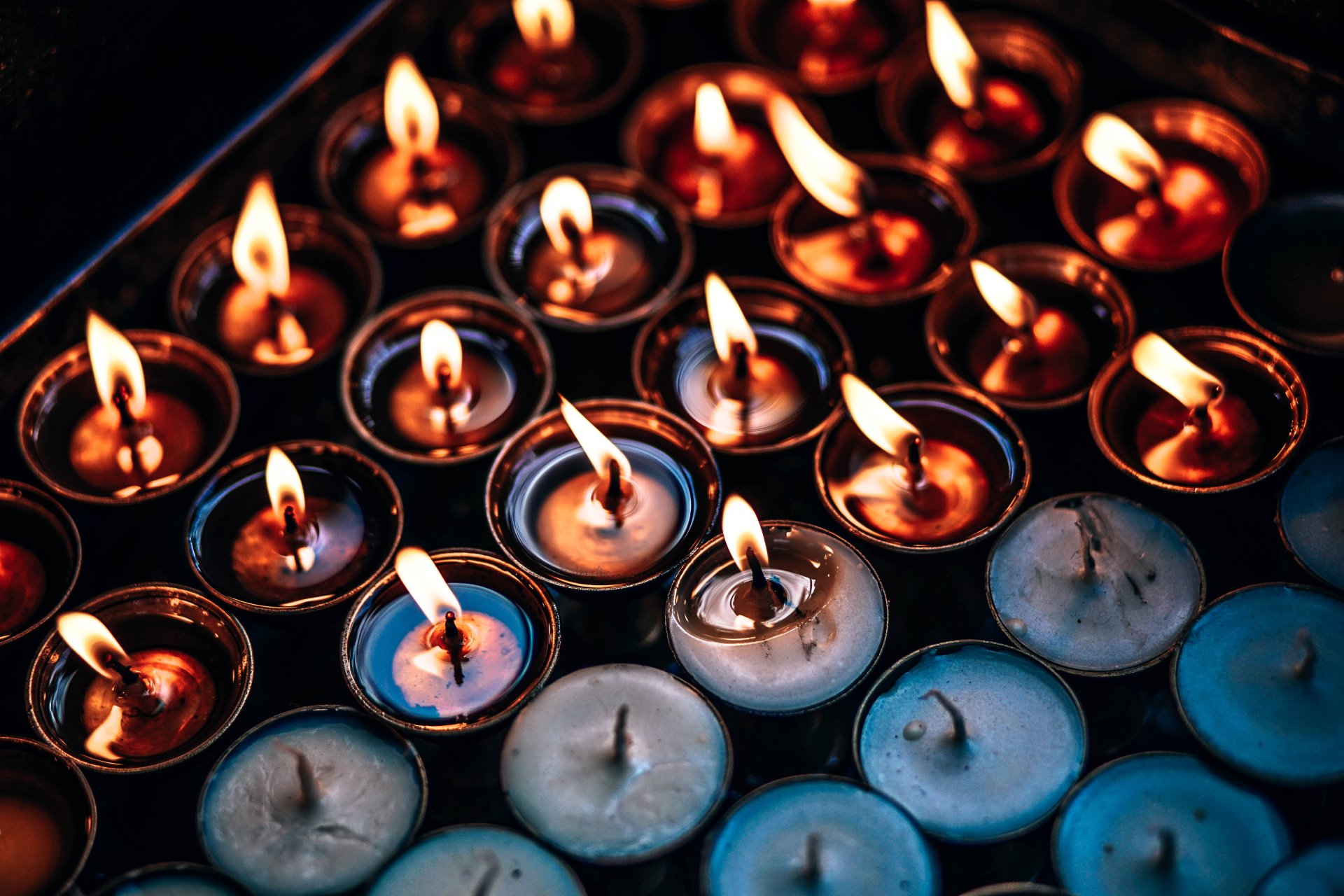 Close-up 4K Ultra HD wallpaper of numerous lit candles with bright flames, showcasing warm orange and yellow tones in a dark setting.