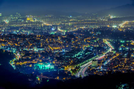 HD wallpaper featuring a vibrant night cityscape of Seoul, South Korea, with colorful city lights illuminating the urban landscape and creating a mesmerizing view.