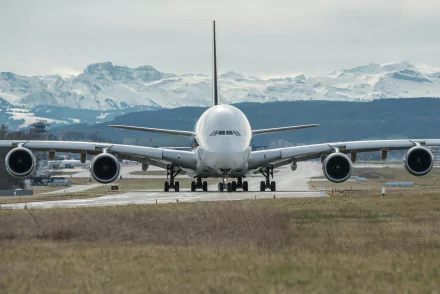 HD desktop wallpaper featuring an Airbus A380 passenger plane on the runway, set against a backdrop of majestic snow-capped mountains.