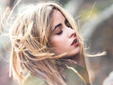 HD desktop wallpaper featuring a blonde woman model with flowing hair and a soft bokeh background, capturing a serene and elegant facial profile.