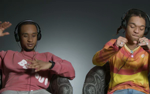 HD wallpaper featuring Rae Sremmurd with headphones, immersed in music against a neutral background.