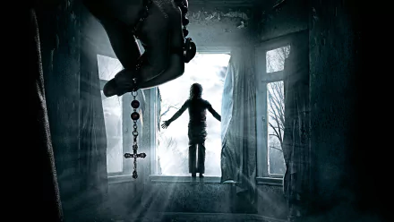 HD wallpaper from The Conjuring 2 shows a dramatic scene with a hand holding a rosary in the foreground, while a silhouetted figure levitates near a window in a dimly lit room.
