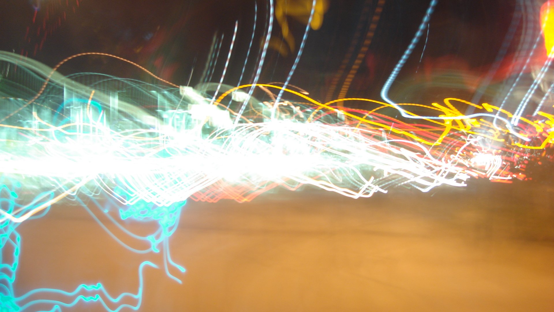 Abstract HD desktop wallpaper featuring vibrant, multicolored light trails creating dynamic, swirling patterns against a dark background.
