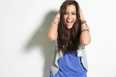 HD desktop wallpaper featuring brunette actress and celebrity Chloe Bennet smiling with brown eyes, radiating joyful energy against a light background.