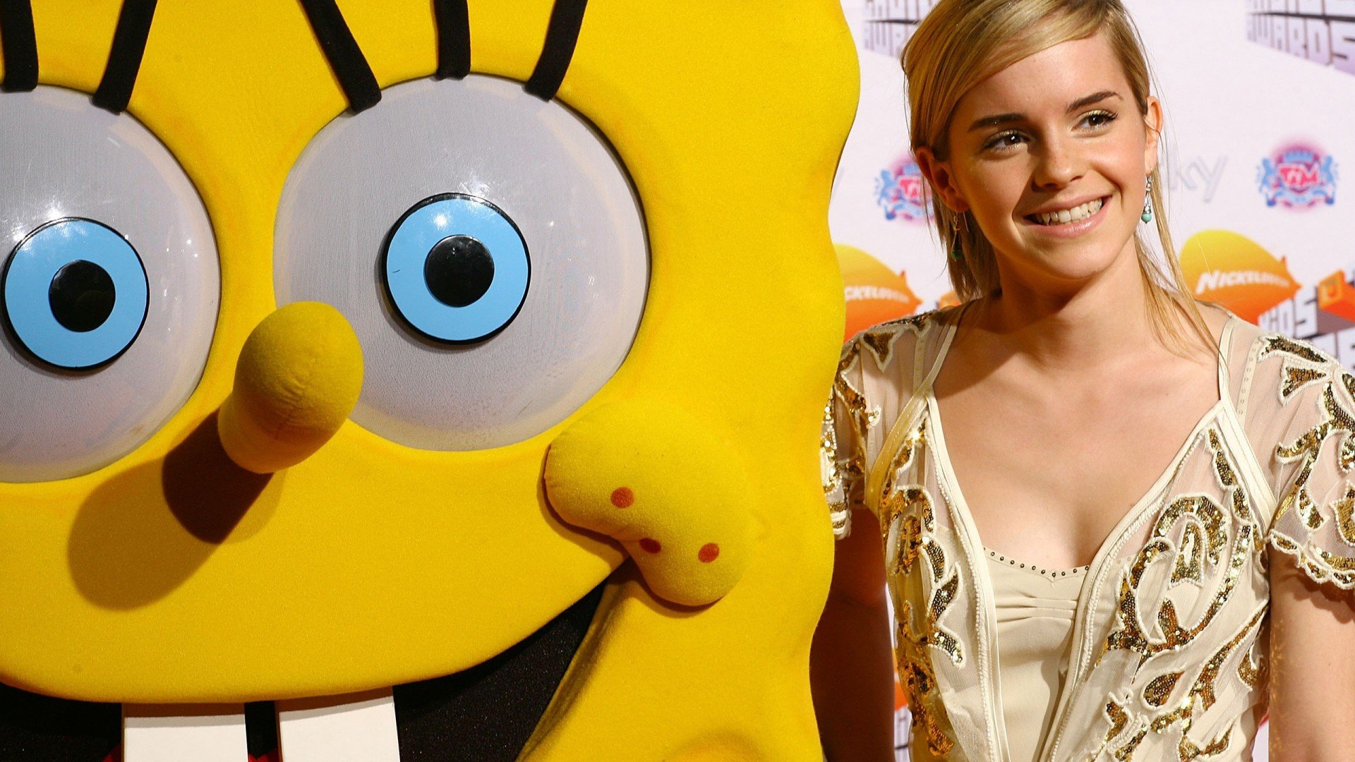 Emma Watson smiles beside a large SpongeBob SquarePants character at an event, captured in a vibrant HD desktop wallpaper background.