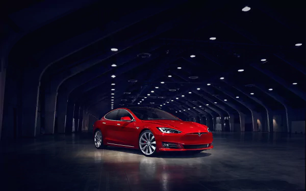 A stunning red Tesla Model S electric car is showcased in a modern, dimly lit setting. This HD desktop wallpaper highlights the sleek design and elegance of Tesla Motors' luxury vehicle.
