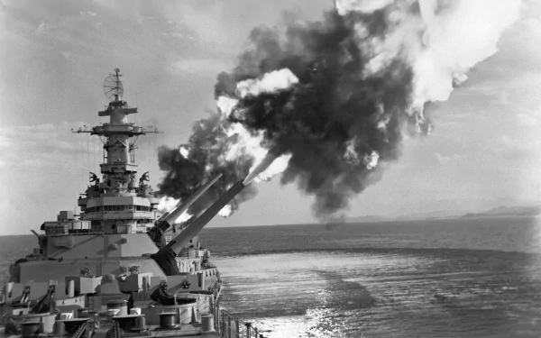 An Iowa-class battleship, USS New Jersey (BB-62), fires its guns in a dramatic display, with smoke billowing against the ocean backdrop. A striking HD wallpaper for military enthusiasts.