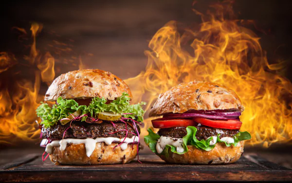 4K Ultra HD PC desktop wallpaper featuring two gourmet burgers with fresh toppings, set against a dramatic background of roaring flames.