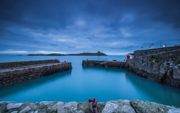 4K Ultra HD PC desktop wallpaper of an Irish harbor: calm blue bay framed by stone piers, cloudy sky and distant horizon