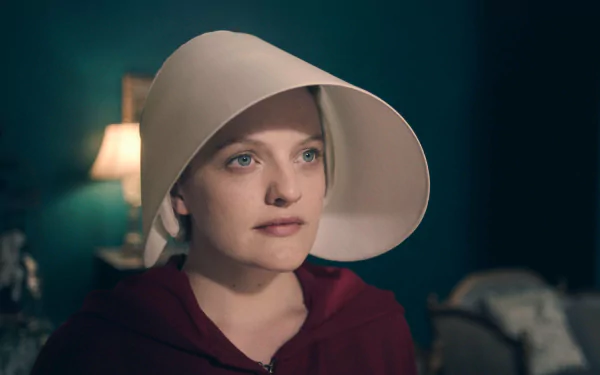 HD wallpaper of a character from The Handmaid's Tale, wearing a red cloak and white bonnet, with a thoughtful expression.