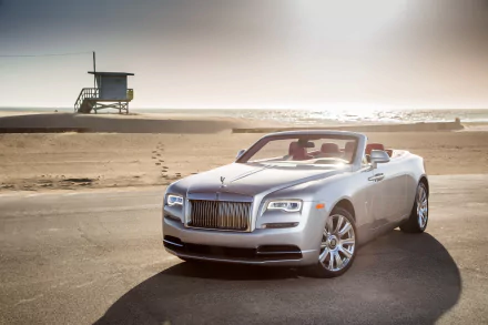 Silver Rolls-Royce Dawn grand tourer convertible parked on a beach road with a lifeguard tower and ocean in the background, showcased in 4K Ultra HD.