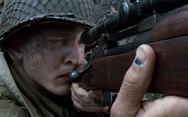 A soldier with a focused expression aims a rifle, encapsulating the intense atmosphere of Saving Private Ryan. This HD wallpaper brings a striking cinematic moment to your desktop.