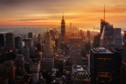 Sunset cityscape of New York showcasing the Empire State Building amidst skyscrapers and man-made structures, captured in an HD desktop wallpaper quality.