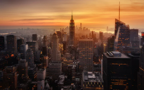 Sunset cityscape of New York showcasing the Empire State Building amidst skyscrapers and man-made structures, captured in an HD desktop wallpaper quality.