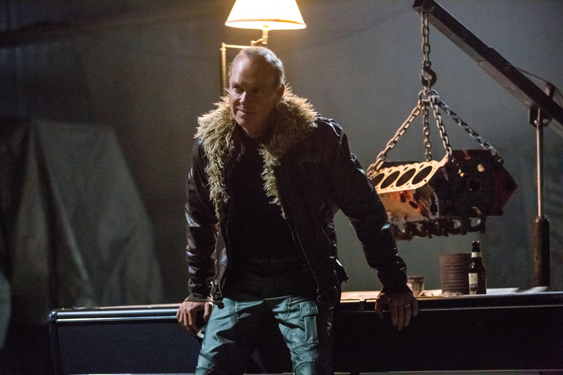 A HD desktop wallpaper from the movie Spider-Man: Homecoming, depicting a character in a dimly lit setting with a rugged jacket and a mechanical background.