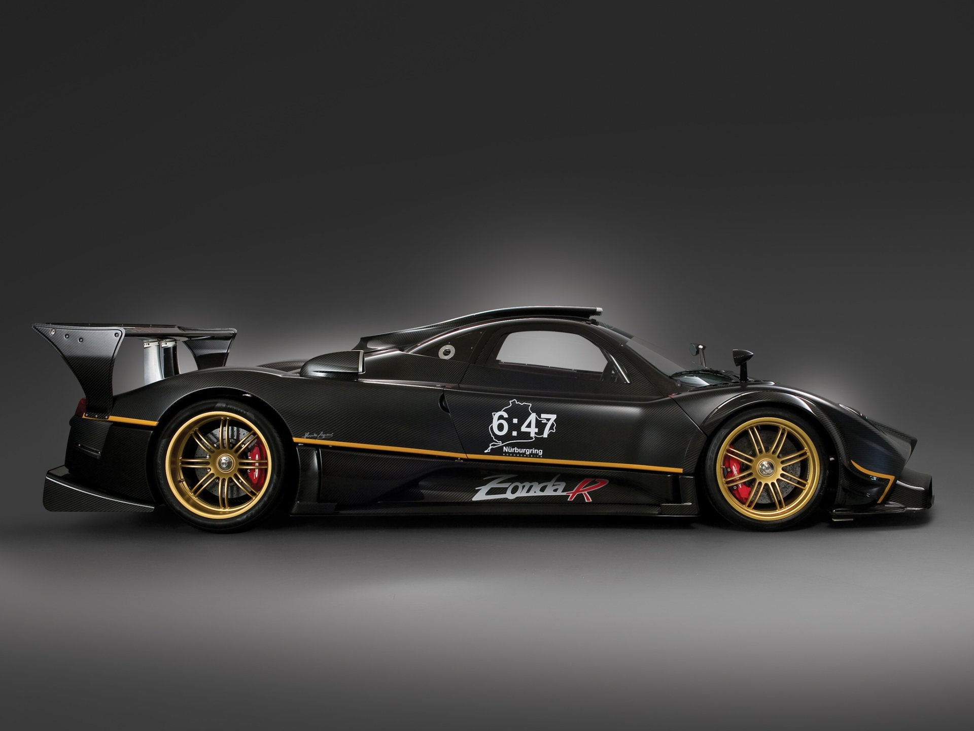 HD desktop wallpaper featuring a sleek black Pagani Zonda R supercar with gold accents, showcasing its aerodynamic design and performance-oriented details.
