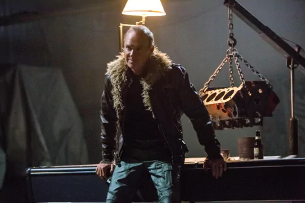 A HD desktop wallpaper from the movie Spider-Man: Homecoming, depicting a character in a dimly lit setting with a rugged jacket and a mechanical background.