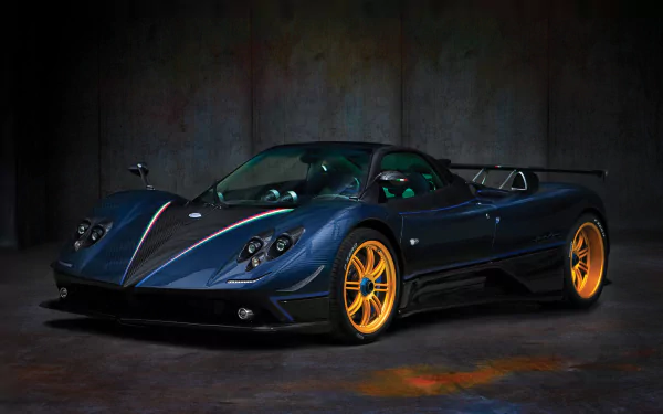 HD wallpaper of a dark blue Pagani Zonda Tricolore supercar with bright orange wheels, showcased against a textured dark background.