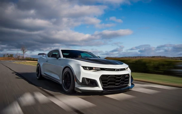 White Chevrolet Camaro ZL1 1LE muscle car speeding along a road under blue skies — 2K Quad HD PC desktop wallpaper.