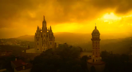 Panoramic HD wallpaper of Tibidabo Cathedral and tower in Barcelona, glowing under a vibrant golden sunset sky.