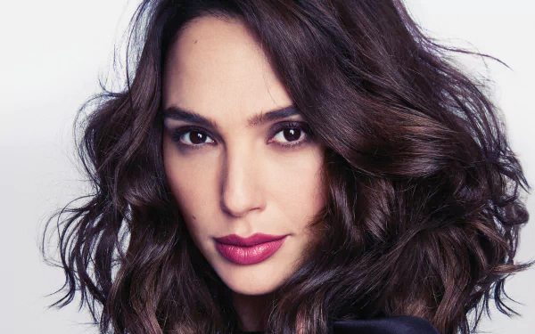 Close-up HD desktop wallpaper of Gal Gadot, Israeli actress and model, with brunette hair, brown eyes, and bold lipstick against a plain background.