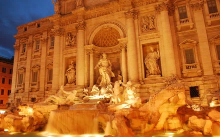 HD PC desktop wallpaper featuring the illuminated Trevi Fountain, showcasing intricate man-made statues and historic building architecture at dusk.