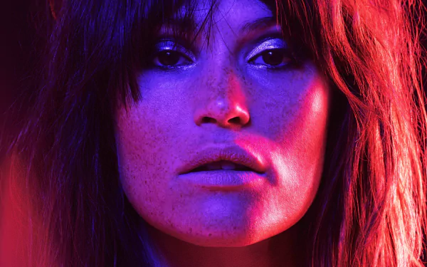 Close-up 4K Ultra HD wallpaper of celebrity Gemma Arterton bathed in vibrant neon purple and red lighting, enhancing her striking features.