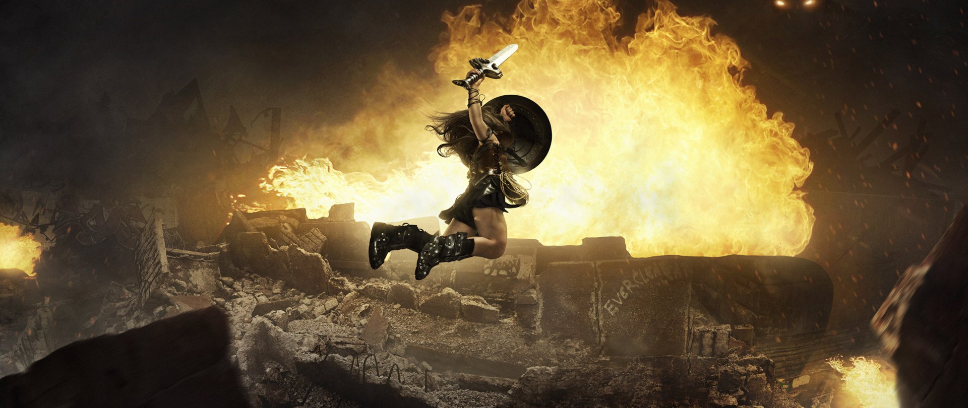 HD desktop wallpaper featuring Wonder Woman leaping with a sword and shield amid an explosive background.