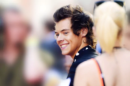 HD desktop wallpaper of a smiling person with stylish hair, tagged as Louis Tomlinson, on a blurred background.