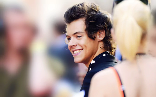 HD desktop wallpaper of a smiling person with stylish hair, tagged as Louis Tomlinson, on a blurred background.