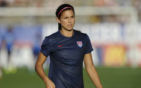 HD desktop wallpaper featuring a focused soccer player in a USA jersey, representing Alex Morgan as a background theme.