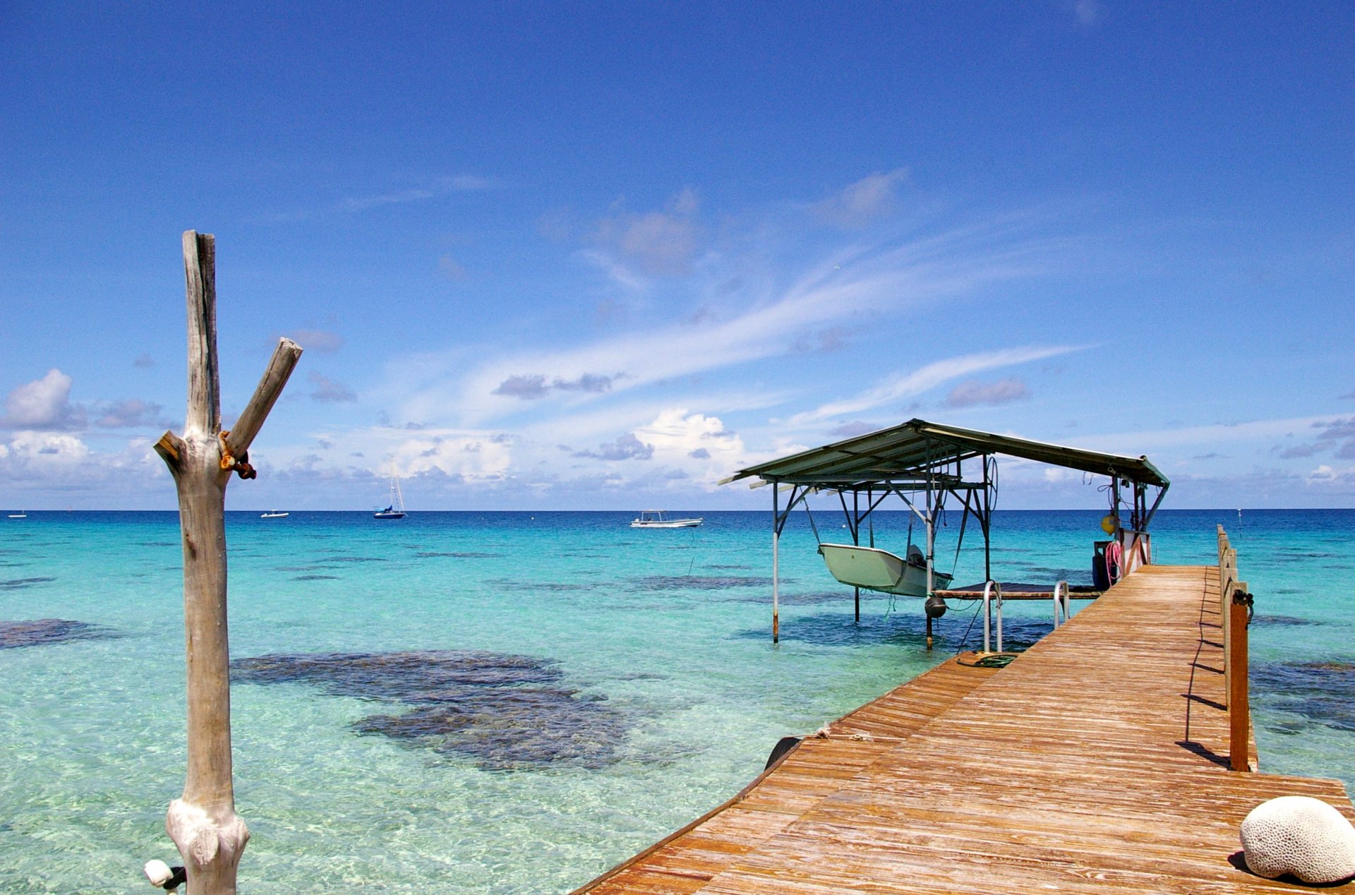 A serene beach scene featuring a wooden pier extending over clear blue waters, under a sky filled with clouds, creating a tranquil atmosphere at a picturesque coastline.