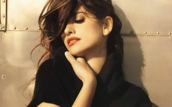 HD desktop wallpaper featuring celebrity Penelope Cruz with a serene expression, eyes closed, and a hand resting near her neck against a metallic background.