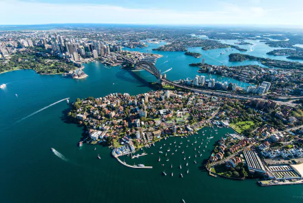 A stunning aerial view of Sydney Harbour, featuring the iconic Sydney Harbour Bridge and bustling cityscape, with numerous boats dotting the water. This HD image captures the vibrant essence of the city and horizon.